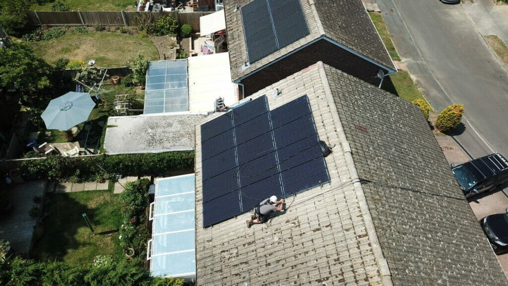 technician pigeon proofing solar panels on a roof